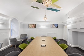 A long table with nine armchairs around it. There are two more armchairs and a coffee table nearby.