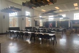 A large room with five long tables and chair surrounded each of them.