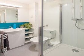 A bathroom with a toilet, shower cubicle, sink and mirror.