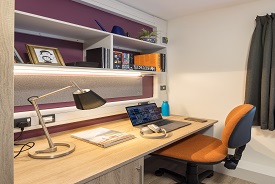 A desk with an office chair, and a set of shelves above it.