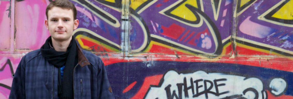 Man in front of a wall with graffiti. The word 