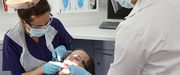 Students treating patient in dental chair.