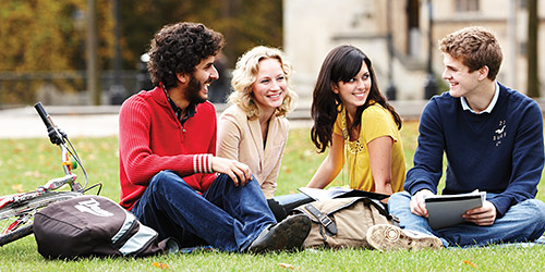 A group of students relaxing together on the grass in a park.