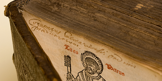 Close up of an open book with image of St Peter holding a key.