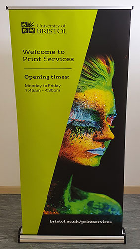 Image showing one of our branded Print Services roller banners with a green and black background showcasing the print quality with an image of a multi-colour iridescent ladies head
