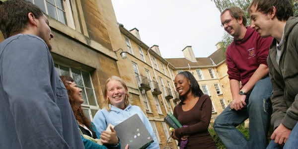 A group of people talking and laughing together outside a building.