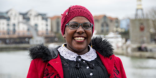 Smiling student facing the camera with Bristol harbourside in the background.