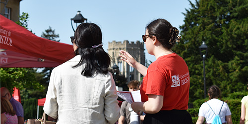 Student ambassador directing a guest at an open day with Wills Memorial Building in the background