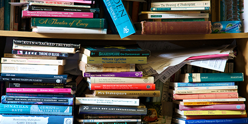 A close up of lots of books stacked on top of each other on book shelves.