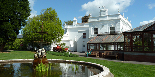 Gardens, fountain and large white building at Langford campus.