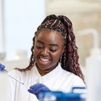 Student in a lab coat and gloves uses a pipette