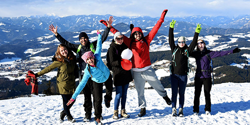 Group of people with arms raised on a snowy mountain.