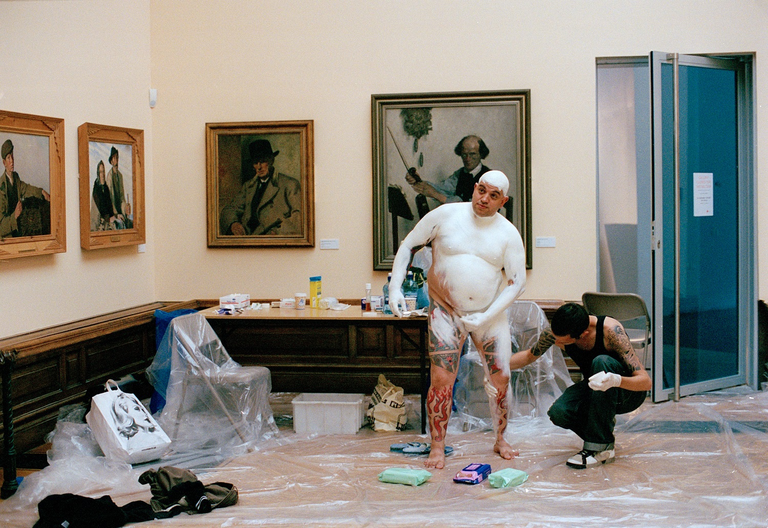 Franko B in an art gallery being covered in white body paint before a performance