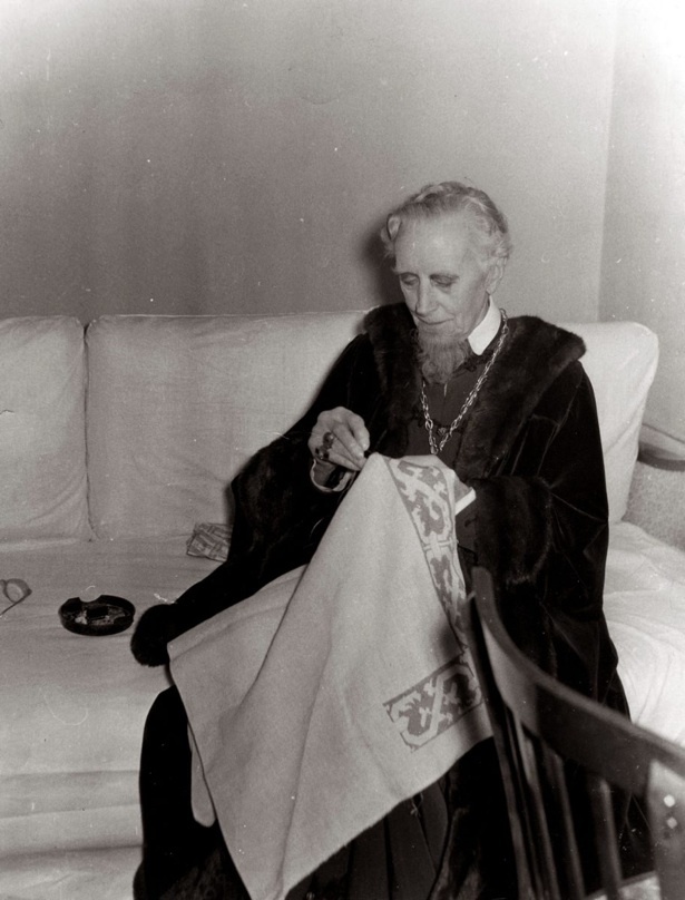 Ernest Thesiger as in costume as Polonius, backstage working on a piece of embroidery 