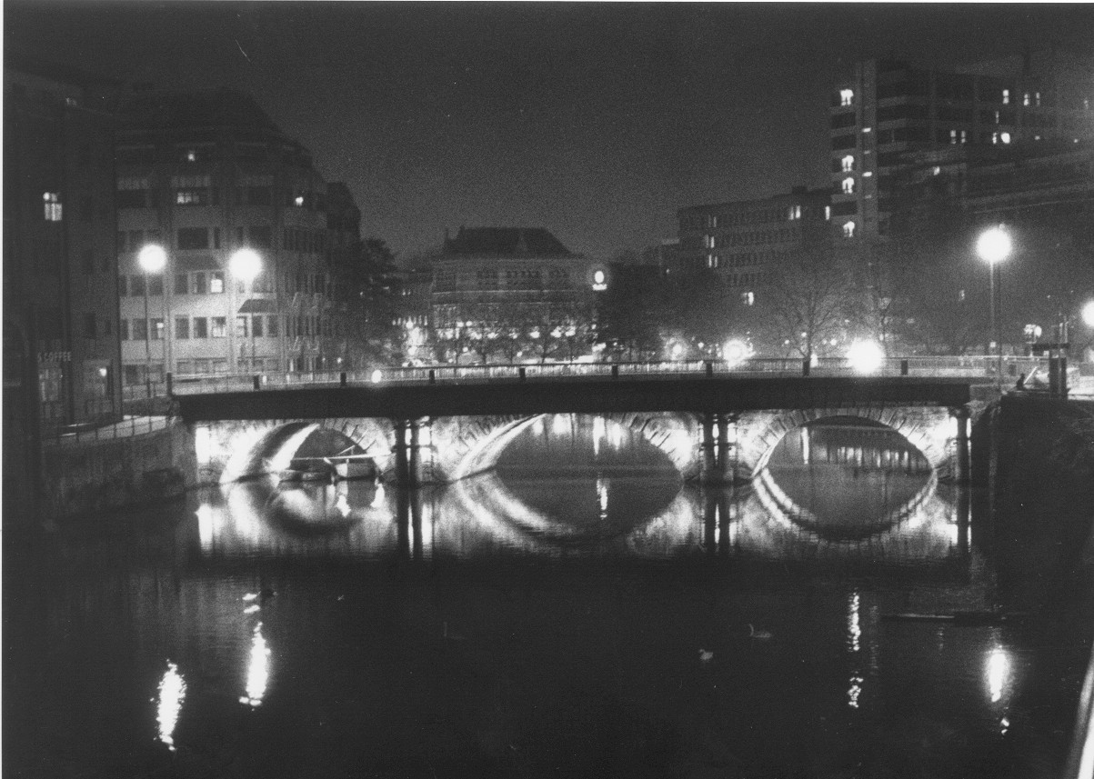 photograph of an illuminated bridge at night reflected on water
