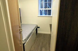 A bedroom with a single bed in one corner and a clothes cupboard opposite.
