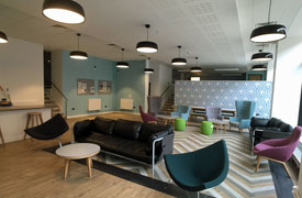 A large room with two black leather sofas and several armchairs and coffee tables.