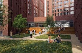 A courtyard outside a brick building. Students are walking and chatting together.