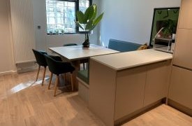 A kitchen with a table, chairs and cupboards.