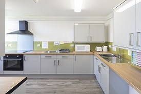 A kitchen with two sinks, an oven and a hob, and several cupboards.