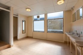 A room with several sinks and mirrors, and doors leading to a toilet cubicle and a shower cubicle.