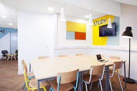 A room with a large table and 10 chairs around it. There is a television screen on the wall and the word 'study' painted above it.