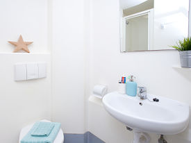 A bathroom with a toilet, sink and mirror.