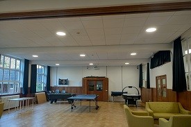 A large room with a pool table, air hockey table and comfy seats.