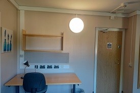 A desk with a chair and shelves above. Door to the far right of the room.