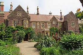 Exterior of a large three-storey red brick redidential building, with a garden in front of it.
