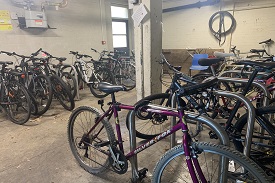 A room with two rows of bike stands and many bikes chained to them.