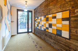 A hallway with a door leading outside at the end, and a row of mailboxes set into another wall.