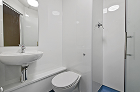 A bathroom with a toilet, shower cubicle, sink and mirror.