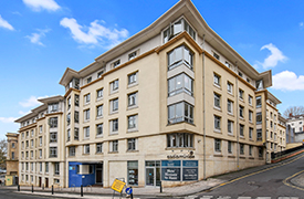 Exterior of a large six-storey sandstone building on the corner of two roads.