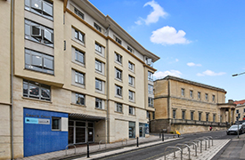 Exterior of a six-storey sandstone building. 'Dean's Court' is written on the wall by the entrance.