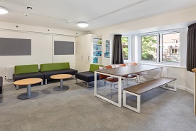 A room with three chairs and a bench around a table, and four armchairs around two coffee tables.