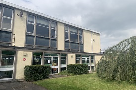 A yellow two-storey building with the word 'source' written on each ground floor door and window.