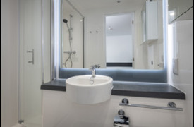 The inside of an ensuite bathroom with a visible shower, sink, and mirror.