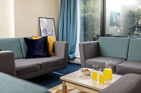 Two grey sofas with cushions with a small coffee table positioned in between the sofas. The coffee table has juices and snacks on the table.