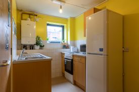 A kitchen with a sink, an oven and hob, a fridge freezer and some cupboards and drawers.