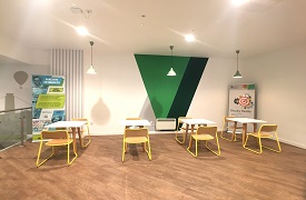 A room with a row of four tables, each with two chairs around it.