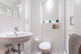 A bathroom with a toilet, sink, mirror and shower cubicle.