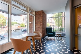 A room with two chairs around a high table, and an armchair and a smaller table nearby.