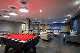 A large room with several sofas and armchairs, a pool table and a ping pong table.
