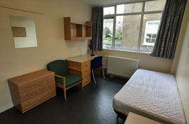 View of bedroom showing single bed, desk and chair, armchair, storage units, shelves and radiator