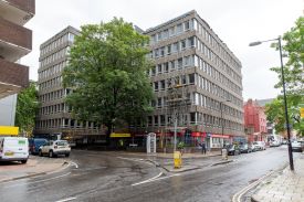 The exterior of a modern seven-storey building on the corner of two roads.