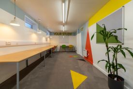 A long room with desks lined up against the walls and some chairs at the desks. The words 'your study' are written on the far wall.