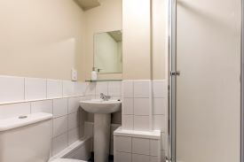 A bathroom with a toilet, sink, mirror and shower cubicle.