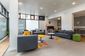 A room with three sofas and two armchairs arranged in a semi-circle around two small tables.