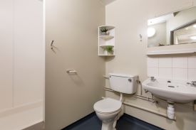 A bathroom with a toilet, sink, mirror and shower cubicle.